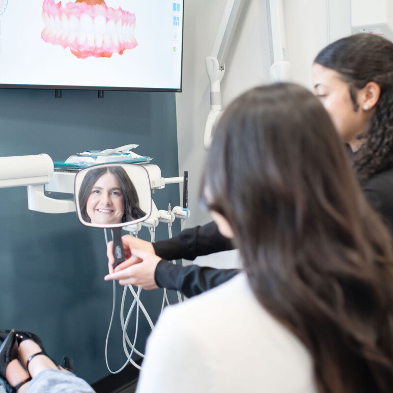 Hygienist holding mirror for patient during dental cleaning