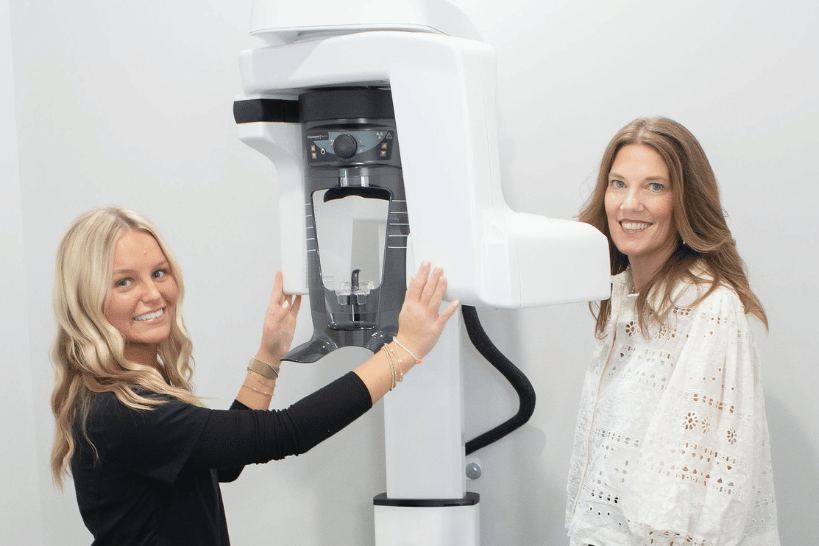 Dental assistant guiding patient through 3D imaging scan.